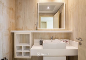A modern bathroom with a white vanity, a large mirror, and a sink.