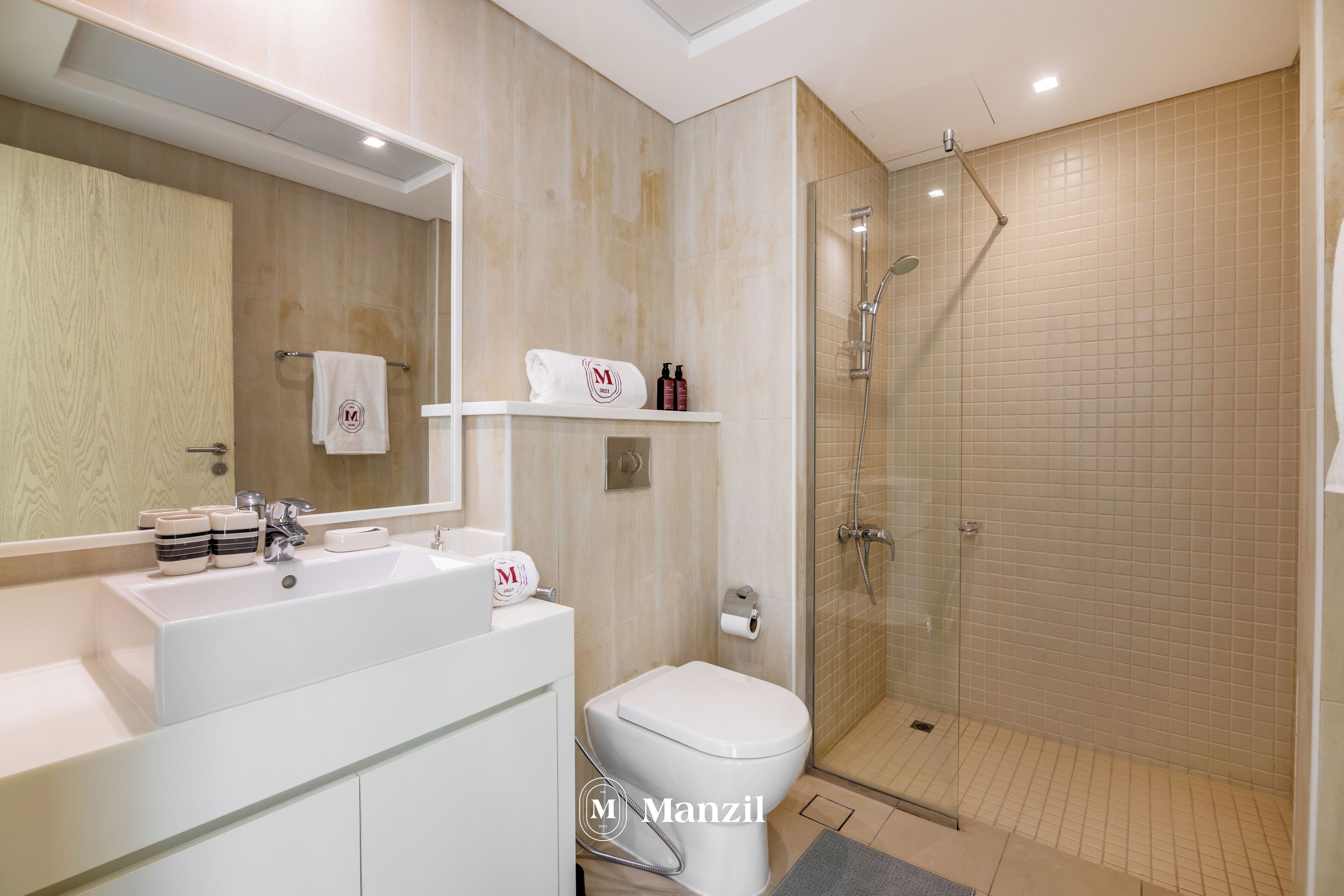 Une salle de bain moderne avec un grand miroir, un lavabo blanc et une douche à parois de verre.