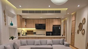 A modern living room with a sectional sofa, a coffee table, and a kitchen in the background.