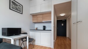 Una cocina compacta con microondas, cafetera y un pequeño comedor con una silla.