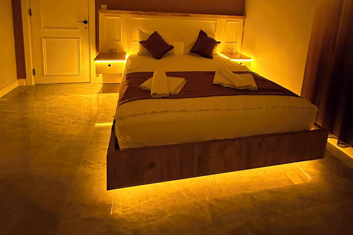 A bedroom with a bed, bedside tables, an air conditioning unit, and a door.