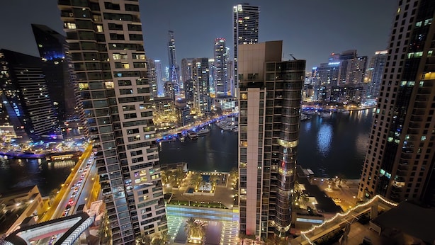 A nighttime cityscape with high-rise buildings, a river, and a bridge. - Highend Luxury Rimal with JBR view (Dubai)
