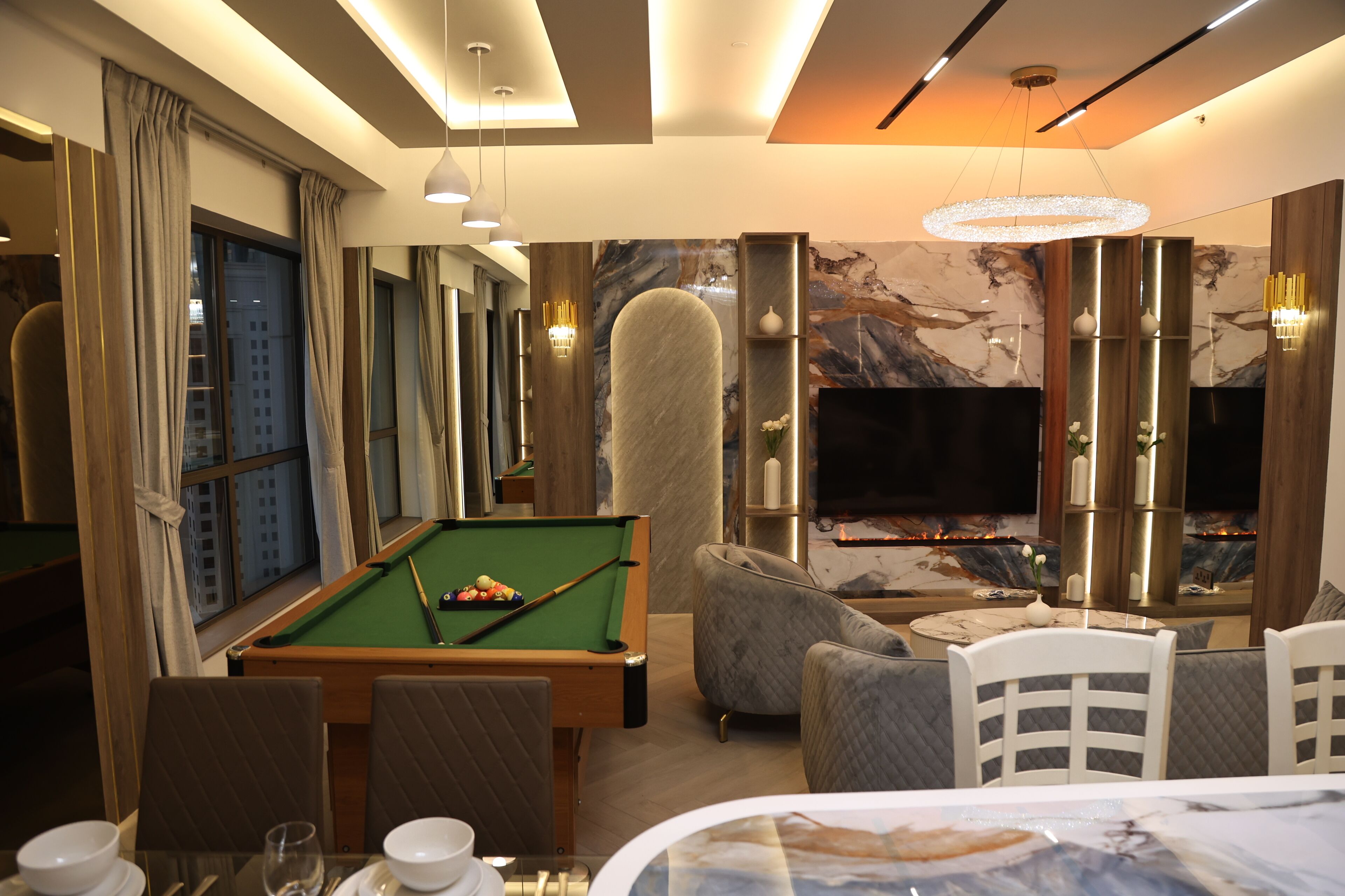 Een moderne hotelkamer met een pooltafel, zachte zithoek, een flatscreen televisie en een open haard.