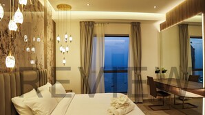 A modern hotel room with a large bed, a dining table, and a view of the sea. - Highend Bahar Ultra Luxury Stay (Dubai)