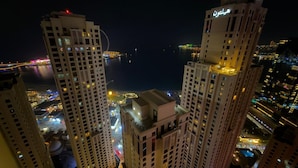 High-rise buildings with illuminated windows and a view of a body of water at night. - Highend Bahar Ultra Luxury Stay (Dubai)