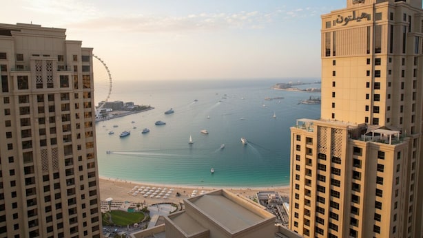 A high-rise hotel overlooking a marina with boats and a beach. - Highend Bahar Ultra Luxury Stay (Dubai)