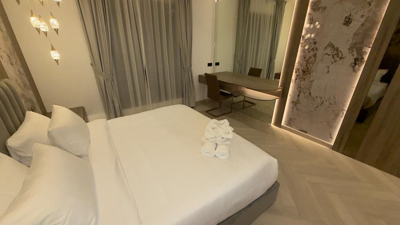 Una habitación de hotel moderna con una cama bien hecha, un escritorio y un espejo grande.