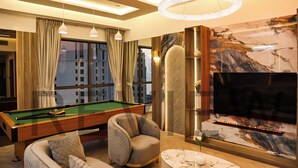 A modern living room with a pool table, comfortable seating, a flat-screen TV, and a marble accent wall. - Highend Bahar Ultra Luxury Stay (Dubai)