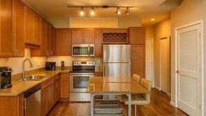A kitchen with wooden cabinets, stainless steel appliances, a granite countertop, and a built-in bench. - Forest Park Skyline Retreat with Balcony, Pool & Parking (St. Louis)