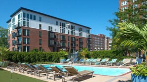 A hotel with a swimming pool, lounge chairs, and a brick facade. - Forest Park Skyline Retreat with Balcony, Pool & Parking (St. Louis)
