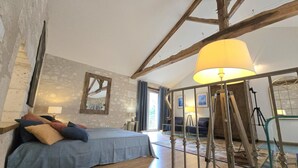 A bedroom with a bed, a lamp, a mirror, and a staircase. - Cozy apartment in the heart of Brantôme, private terrace (Brantôme en Périgord-Brantôme en Périgord)