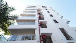 A multi-story building with balconies, windows, and a fire hose on the exterior. - EXCELLENT HOMES (Nashik)