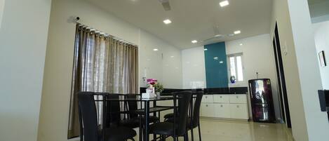 Una cucina moderna con zona pranzo, dotata di ventilatore a soffitto, illuminazione a incasso e frigorifero.