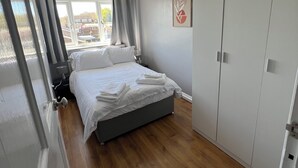 A bedroom with a bed, a wardrobe, and a window. - Spacious 3 Bed Home - Ideal for Families & Groups (Linford)