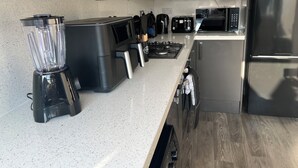A modern kitchen with stainless steel appliances, including a blender, toaster, and microwave. - Spacious 3 Bed Home - Ideal for Families & Groups (Linford)