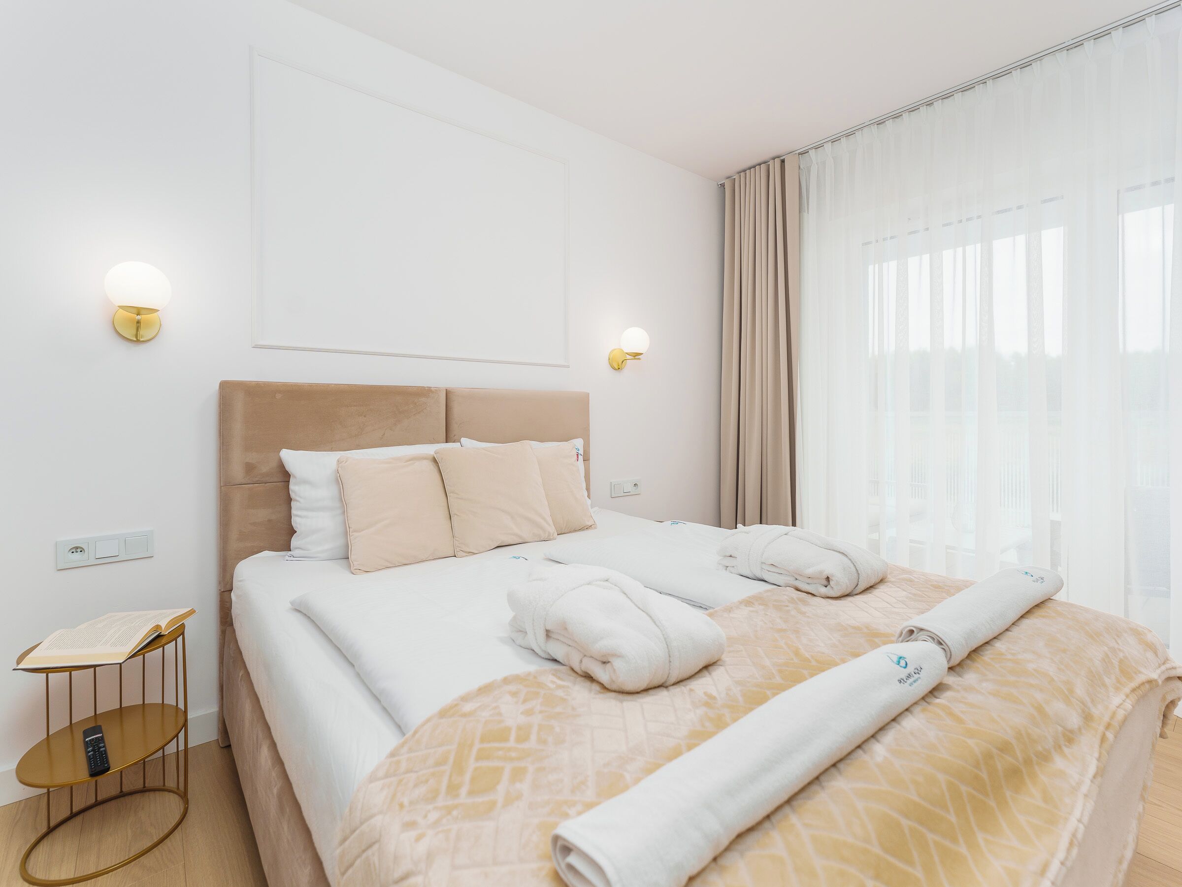 Ein Hotelzimmer mit Bett, Nachttischlampen, einem Nachttisch und einem mit Vorhängen versehenen Fenster.