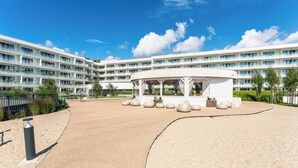 Ett modernt hotell med en central innergård, flera balkonger och en klarblå himmel.