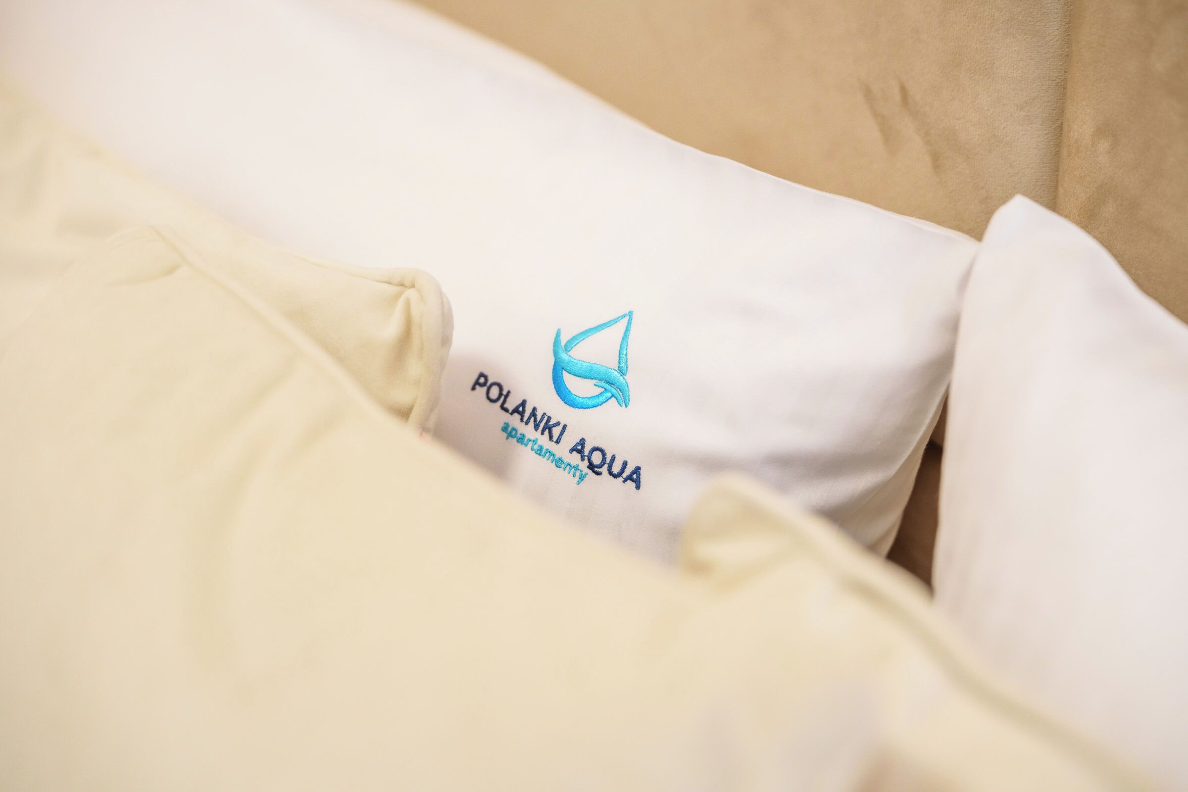 A pillow with the text "POLANKI AQUA apartment" and a logo.