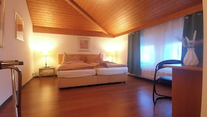 A cozy bedroom with a wooden ceiling, a bed with pillows, a nightstand, a chair, and a vase with flowers. - il Fiore - Hotel Ristorante Pizzeria (Steinach)