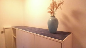 A corner of a room with a white cabinet and a blue vase with dried plants on top. - il Fiore - Hotel Ristorante Pizzeria (Steinach)