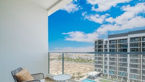 A balcony with a clear view of a modern building and a swimming pool. - LUX Dubai Hills Sway Studio (Dubai)