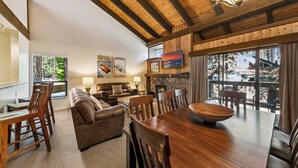 A cozy living room with a fireplace, wooden ceiling beams, and a large dining table. - Family Tahoe Retreat: Beach, Pool & Hot Tub LLV401 (South Lake Tahoe)