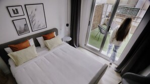 Een hotelkamer met een groot bed, een klein rond tafeltje en een balkon met een stoel.
