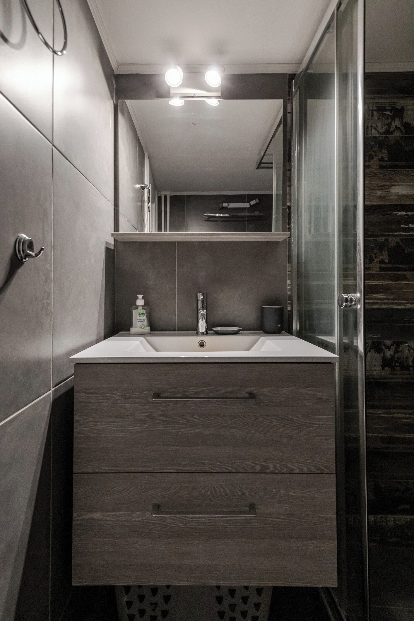 A modern bathroom with a large mirror, a sink, and a shower enclosure.