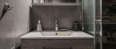 A modern bathroom with a large mirror, a sink, and a shower enclosure.