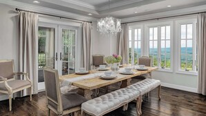A dining room with a wooden table set for four, a bench, and a chandelier.