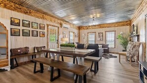 A spacious living room with a wooden bench, a sofa, and a dining table. - Americana Farm Getaway! Hot Tub, Views, Firepit (Valley Head)