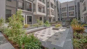 Een modern woongebouw met meerdere balkons, een binnentuin met potplanten en een schaakbordpatroon op de vloer.