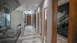 Een moderne hal met een gestreept vloerkleed, glazen balustrades en houten deuren.