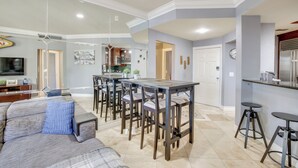 Une cuisine moderne avec un coin bar, une table à manger avec des chaises et un espace salon avec un canapé.