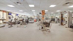 Une salle de sport spacieuse équipée de divers appareils d’exercice, notamment des tapis de course, des appareils de musculation et des poids libres.
