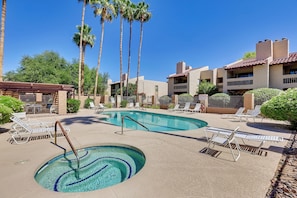 A pool area with lounge chairs and palm trees.