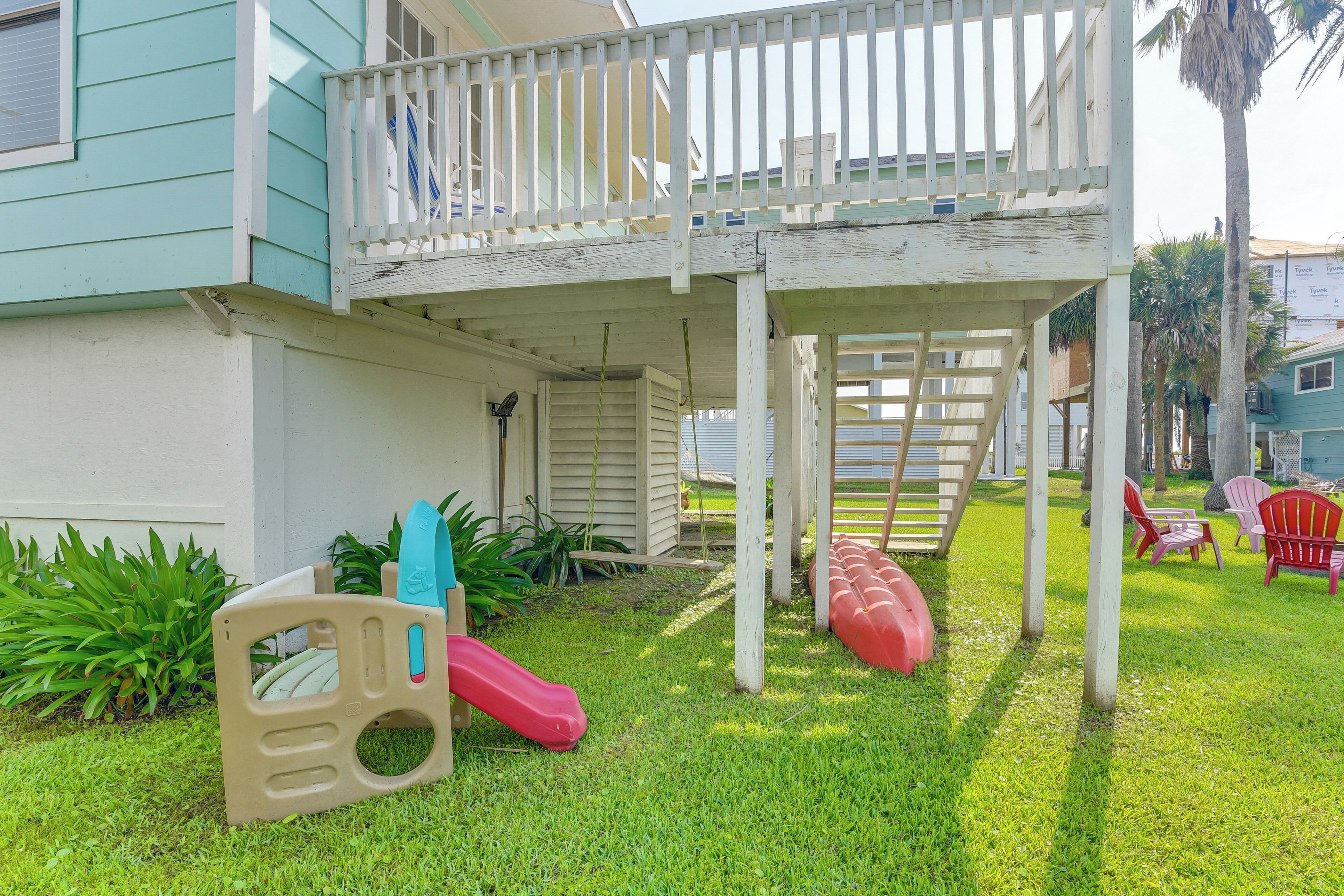 A covered outdoor area with a slide, seating, and a staircase leading to a balcony.