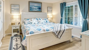 Een slaapkamer met een bed, nachtkastjes, een plafondventilator en een raam met gordijnen.