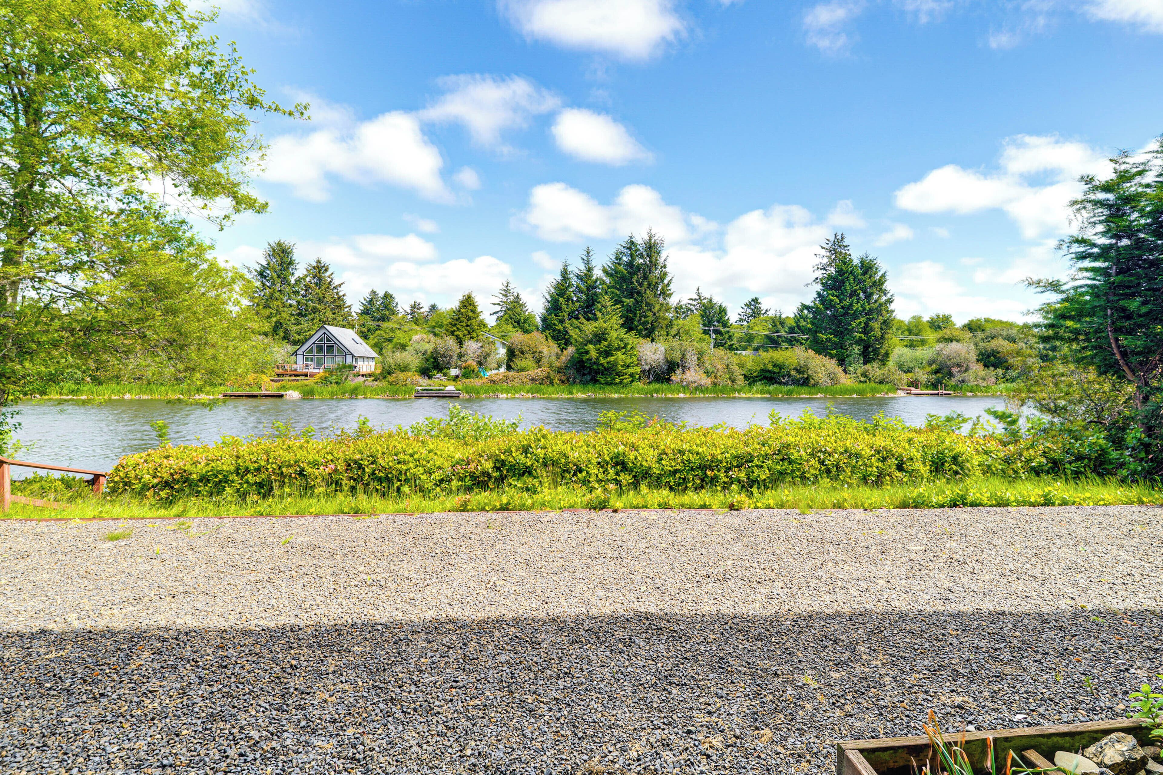 A gravel path leading to a lake with a house in the background.