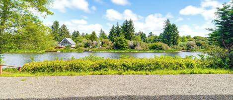 A gravel path leading to a lake with a house in the background.