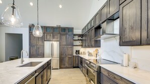 Een moderne keuken met donkere houten kastjes, roestvrijstalen apparatuur en een marmeren aanrecht.
