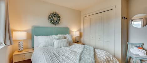 Un dormitorio con cama, mesitas de noche, cómoda, espejo y una puerta.