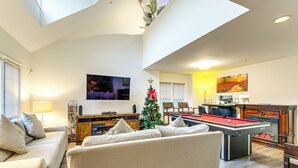 Un salon spacieux avec une table de billard, un canapé et un sapin de Noël.