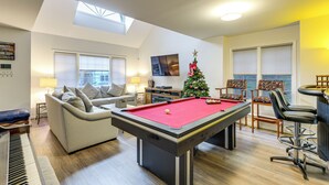 Un salon avec une table de billard, un piano, un canapé et un sapin de Noël.