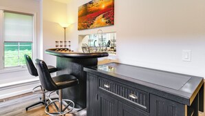 Une cuisine moderne avec un plan de travail noir, deux tabourets de bar, un luminaire suspendu et un grand tableau au-dessus du plan de travail.