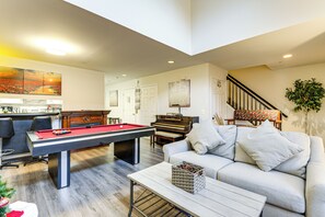 A living room with a pool table, a sofa, a coffee table, a piano, and a staircase. - 8 Mi to Dtwn Silver Spring: Convenient Condo (Silver Spring)