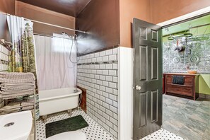 A bathroom with a white bathtub, a shower, and a toilet. There is a towel rack with folded towels and a green mat on the floor. - 2 Mi to Downtown Spokane: Nurse-ready Rental (Spokane)
