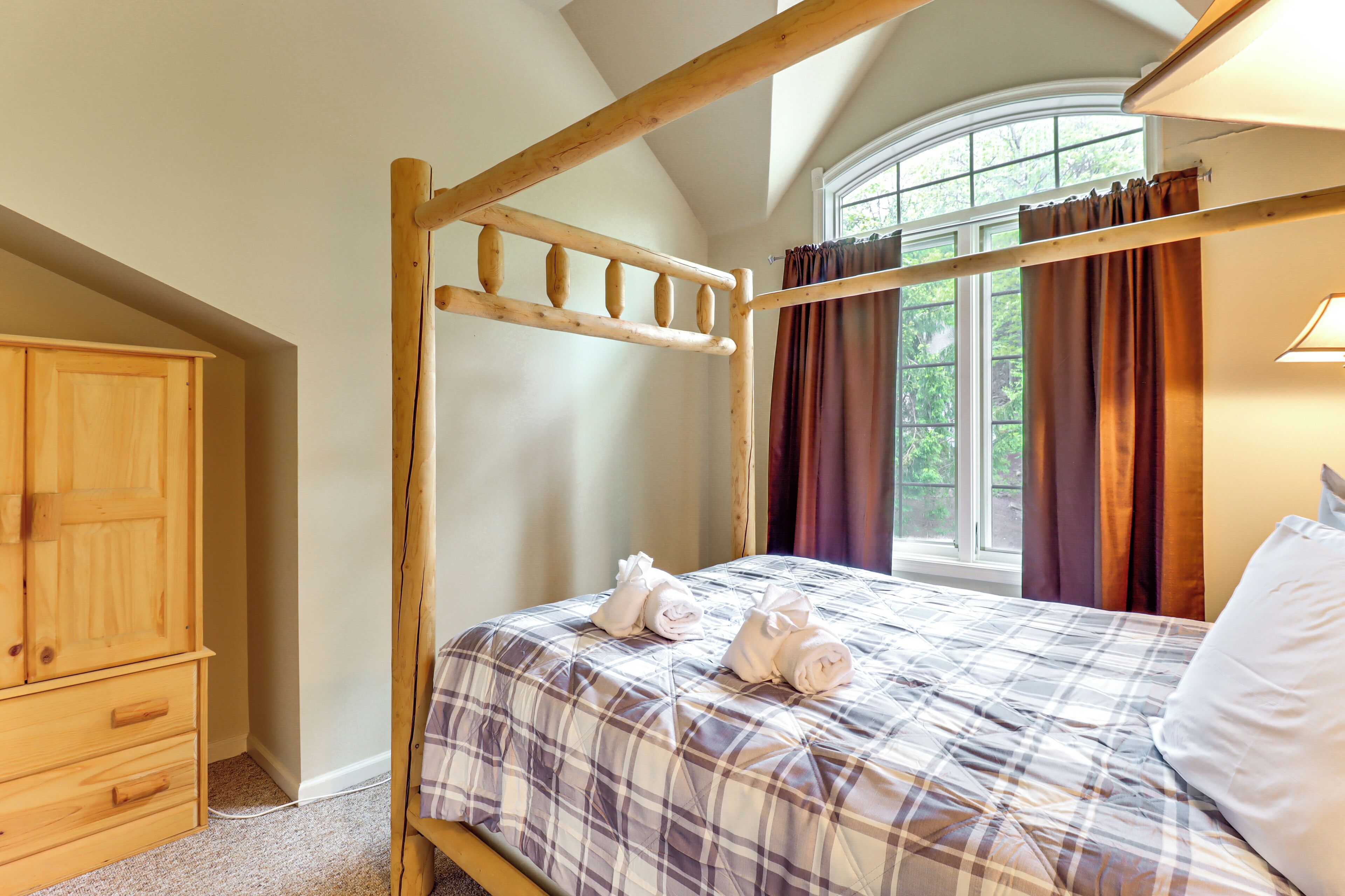Ein Schlafzimmer mit einem hölzernen Himmelbett, einem Holzschrank und einem Fenster mit Vorhängen.