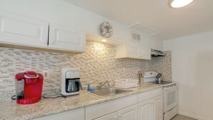 A kitchen with white cabinets, a coffee maker, a kettle, and a sink. - Steps to Sand & Boardwalk! Seaside Heights Condo (Seaside Heights)