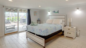 A bedroom with a bed, nightstand, and a view through a sliding glass door to an outdoor patio. - Steps to Sand & Boardwalk! Seaside Heights Condo (Seaside Heights)